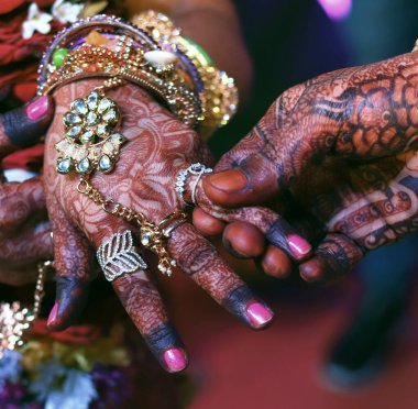 Hintli bir gelinin yumuşak elleri kınalı dövmeli damadın elini tut, yüzük seremonisi.