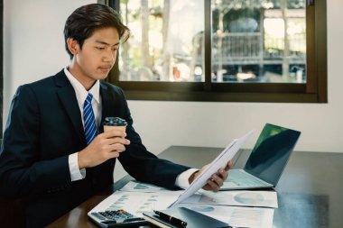 İşadamı, iş hedefleri belirlemek ve yeni hedefe ulaşmayı planlamak için merkez ofisteki bilgisayarı kullanarak grafiği analiz ediyor.