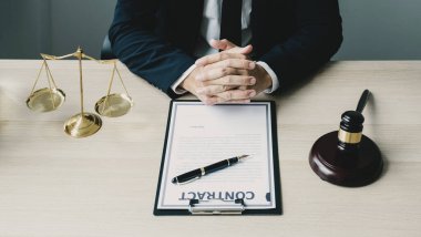 El, Avukat oturuyor ve ofiste hukuki danışmanlık hizmeti veriyor adalet terazisi ve tokmak çekiciyle.