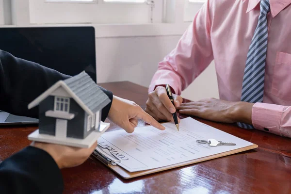 stock image Hand signing on contract after the real estate agent explains the business contract, rent, purchase, mortgage, a loan, or home insurance to the buyer.