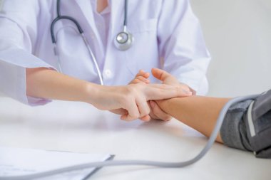 Doktor el hastanın nabzını kontrol eder ve sonuçları kaydeder. Sağlık kontrolü konsepti..