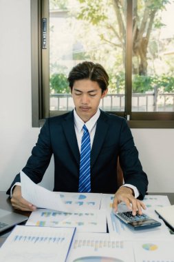 İşadamı, iş hedefleri belirlemek ve yeni hedefe ulaşmayı planlamak için merkez ofisteki bilgisayarı kullanarak grafiği analiz ediyor.