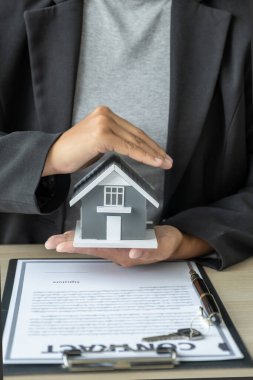 Bir emlakçının eli ev modelini engeller ve iş sözleşmesini, kirayı, satın almayı, ipoteği, krediyi veya ev sigortasını açıklar..
