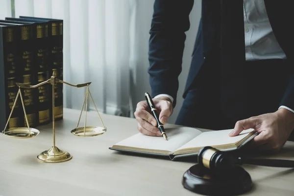 stock image Lawyer hand holding pen and providing legal consult business dispute service at the office with justice scale and gavel hammer.