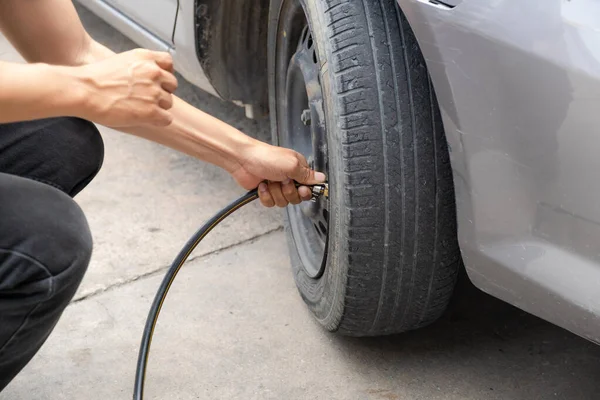 stock image Driver man hand inflating car tire, check to raise the pressure, compressor and maintain wheels inflate.