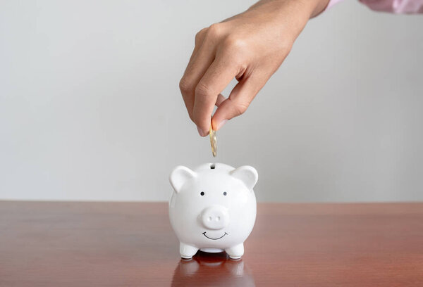 Businessman hand putting bitcoins into white piggybank. risk and wealth can happen in investment savings or trading in cryptocurrency innovation