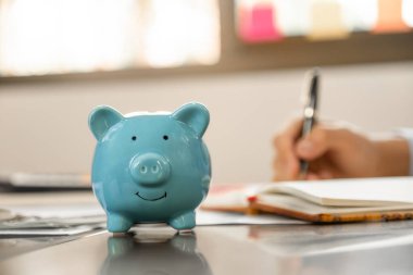 Piggybank, İşadamı gelir ve giderleri dolar banknotlarıyla hesaplamak için el yazısı, başarıya ulaşmak için şirket kurma, gelecek planı ve emeklilik fonu konsepti için para biriktirme.