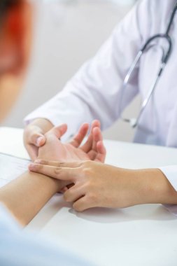 Doktor el hastanın nabzını kontrol eder ve sonuçları kaydeder. Sağlık kontrolü konsepti..