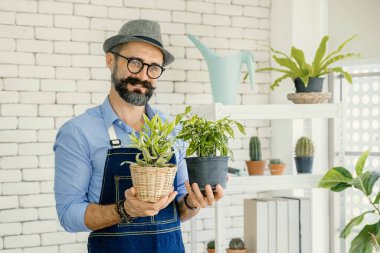 Bıyıklı yaşlı bir adam ya da büyükbaba, emeklilikten sonra ağaç için bahçeyle uğraşmayı sever..