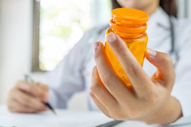 Doktorlar ilaç şişesini tutuyor, sağlık muayenesi sonuçlarını rapor ediyor ve hastalara ilaç öneriyor..