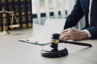 Tokmak çekiç, avukatın eli kalem tutuyor ve ofiste hukuki danışmanlık hizmeti veriyor..