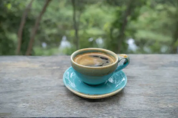 Blue cup of coffee with nature green background.