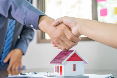 Emlakçılar ve alıcılar iş sözleşmesi imzaladıktan sonra el sıkışırlar, kira, satın alma, ipotek, kredi veya ev sigortası.