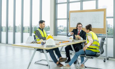 Engineer team is meeting to inspect the construction blueprint drawings, work plan and distribute work before starting the building.