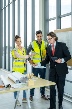 Mühendis ekibi inşaat planı çizimleri, çalışma planı ve binaya başlamadan önce işleri dağıtmak için toplanıyor. dikey