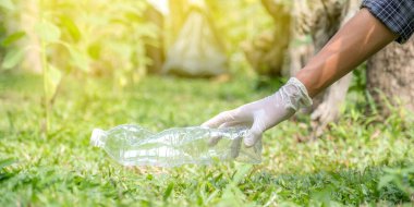 Ellerinde plastik şişelerle çöpleri toplayan çift, Dünya Çevre Günü 'nde Ayçiçeği Parkı' ndaki siyah çöp torbasına atıyorlar..