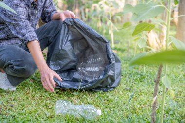 Dünya Çevre Günü 'nde, ayçiçeği parkındaki siyah çöp poşetine atık toplamak..