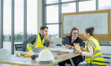 Engineer team is meeting to inspect the construction blueprint drawings, work plan and distribute work before starting the building.