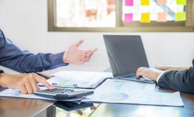İş gelirlerini artırmak için strateji planlamak için el yapımı hesap makinesi, iş kadını ve iş adamları toplantısı. Beyin fırtınası yapan bir finans grafik analizi yapın ve yeni hedef için tartışın..