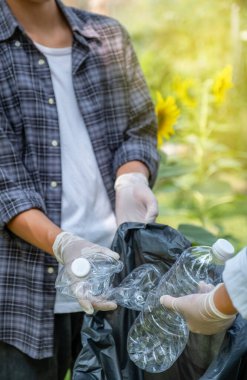 Ellerinde plastik şişelerle çöpleri toplayan çift, Dünya Çevre Günü 'nde Ayçiçeği Parkı' ndaki siyah çöp torbasına atıyorlar..