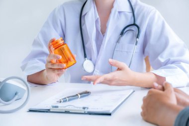 El ele tutuşan ilaç şişeleri, doktorun tavsiyesi sağlık muayenesi sonuçları ve hastalara, mesleki danışmanlık tıbbi kontrol programı konseptine yönelik ilaçlar öneriyor..