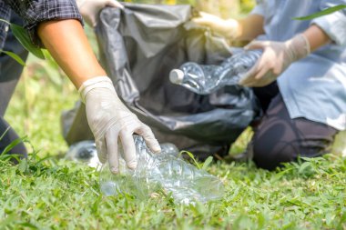Ellerinde plastik şişelerle çöpleri toplayan çift, Dünya Çevre Günü 'nde Ayçiçeği Parkı' ndaki siyah çöp torbasına atıyorlar..