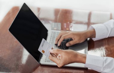 Asyalı genç tüketici işadamları ellerinde sahte kredi kartı ile ev ofisinden gelen dizüstü bilgisayarla indirimli ürünlere göre online alışveriş yapmaya hazırlar..