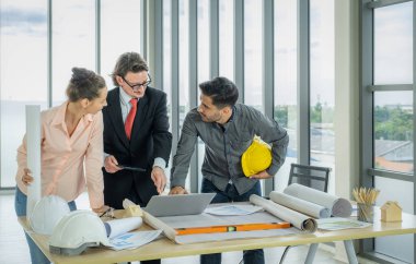 Engineer team is meeting to inspect the construction blueprint drawings, work plan and distribute work before starting the building.