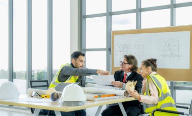 Engineer team is meeting to inspect the construction blueprint drawings, work plan and distribute work before starting the building,