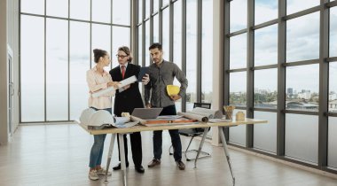 Engineer team is meeting to inspect the construction blueprint drawings, work plan and distribute work before starting the building.