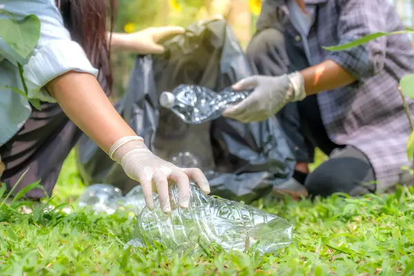 Ellerinde plastik şişelerle çöpleri toplayan çift, Dünya Çevre Günü 'nde Ayçiçeği Parkı' ndaki siyah çöp torbasına atıyorlar..