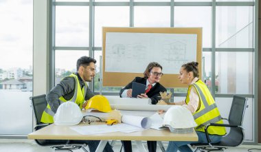 Engineer team is meeting to inspect the construction blueprint drawings, work plan and distribute work before starting the building.
