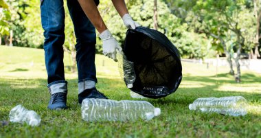 Plastik şişe atıklarını tutan, çöpleri toplayan ve Çevre Dünyası 'ndaki parkta siyah çöp torbasına koyan..