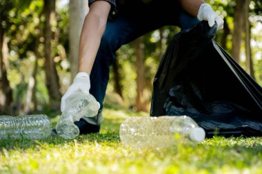 Plastik şişe atıklarını tutan, çöpleri toplayan ve Çevre Dünyası 'ndaki parkta siyah çöp torbasına koyan..