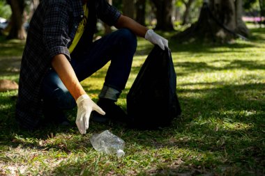 Plastik şişe atıklarını tutan, çöpleri toplayan ve Çevre Dünyası 'ndaki parkta siyah çöp torbasına koyan..