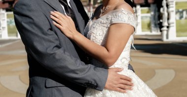 Gelin, damadın yanında duruyor uluslararası giysili çiftlerin fotoğraflarını çekiyor. Aşk Çifti Düğün Günü, Sevgililer Günü konsepti.