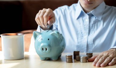 Kadınlar altın sikkeyi pembe kumbaraya koyuyor ve online pazarlama için dizüstü bilgisayar kullanıyor. Suşi için iş kuruyor, gelecek planı ve emeklilik fonu konsepti için para biriktiriyor..