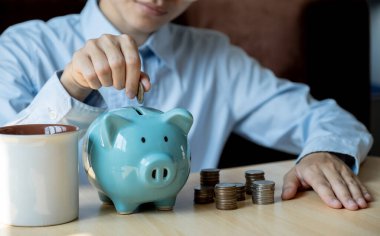 Kadınlar altın sikkeyi pembe kumbaraya koyuyor ve online pazarlama için dizüstü bilgisayar kullanıyor. Suşi için iş kuruyor, gelecek planı ve emeklilik fonu konsepti için para biriktiriyor..