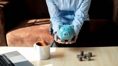 Kadınlar altın sikkeyi pembe kumbaraya koyuyor ve online pazarlama için dizüstü bilgisayar kullanıyor. Suşi için iş kuruyor, gelecek planı ve emeklilik fonu konsepti için para biriktiriyor..