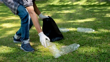 Plastik şişe atıklarını tutan, çöpleri toplayan ve Çevre Dünyası 'ndaki parkta siyah çöp torbasına koyan..