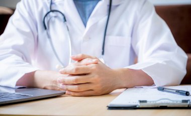 Doktor ellerini hastanedeki çalışma masasına yapıştırmış oturuyor..