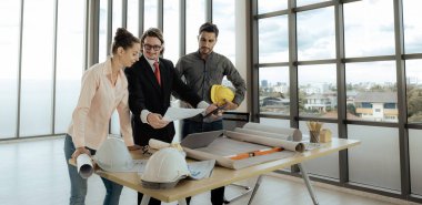 Engineer team is meeting to inspect the construction blueprint drawings, work plan and distribute work before starting the building.