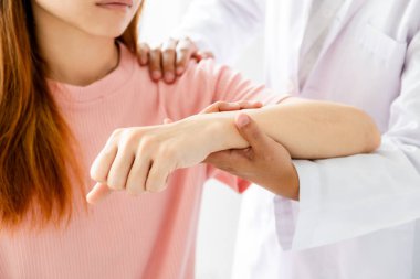 Kadın doktor bir hastanın omzunu uzatarak el tedavisi görüyor. Gerilme egzersizleri ile tedavi.