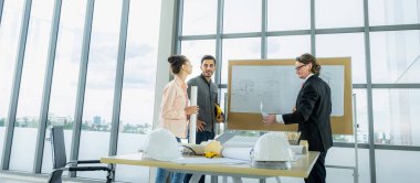 Engineer team is meeting to inspect the construction blueprint drawings, work plan and distribute work before starting the building.