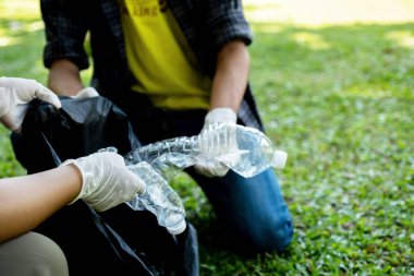 Ellerinde plastik şişelerle çöpleri toplayan bir çift, Dünya Çevre Günü 'nde halka açık parktaki siyah çöp torbasına atıyorlar..