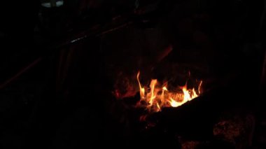 Kömür ocağındaki ateş, geceleri doğal bir kamp alanında yemek pişirmek için eti kızarttı..