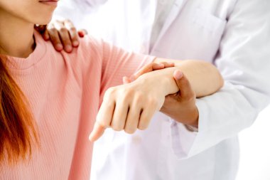 Kadın doktor bir hastanın omzunu uzatarak el tedavisi görüyor. Gerilme egzersizleri ile tedavi.