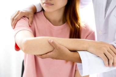 Kadın doktor bir hastanın omzunu uzatarak el tedavisi görüyor. Gerilme egzersizleri ile tedavi.