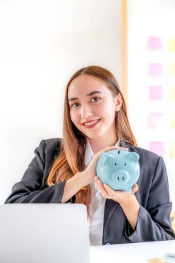 Kafkasyalı kadın domuz kumbarası tutuyor, başarılı olmak için iş kuruyor, gelecek planı ve emeklilik fonu kavramı için para biriktiriyor..
