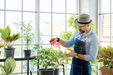Bıyıklı yaşlı bir adam ya da büyükbaba, emeklilikten sonra ağaç için bahçeyle uğraşmayı sever..
